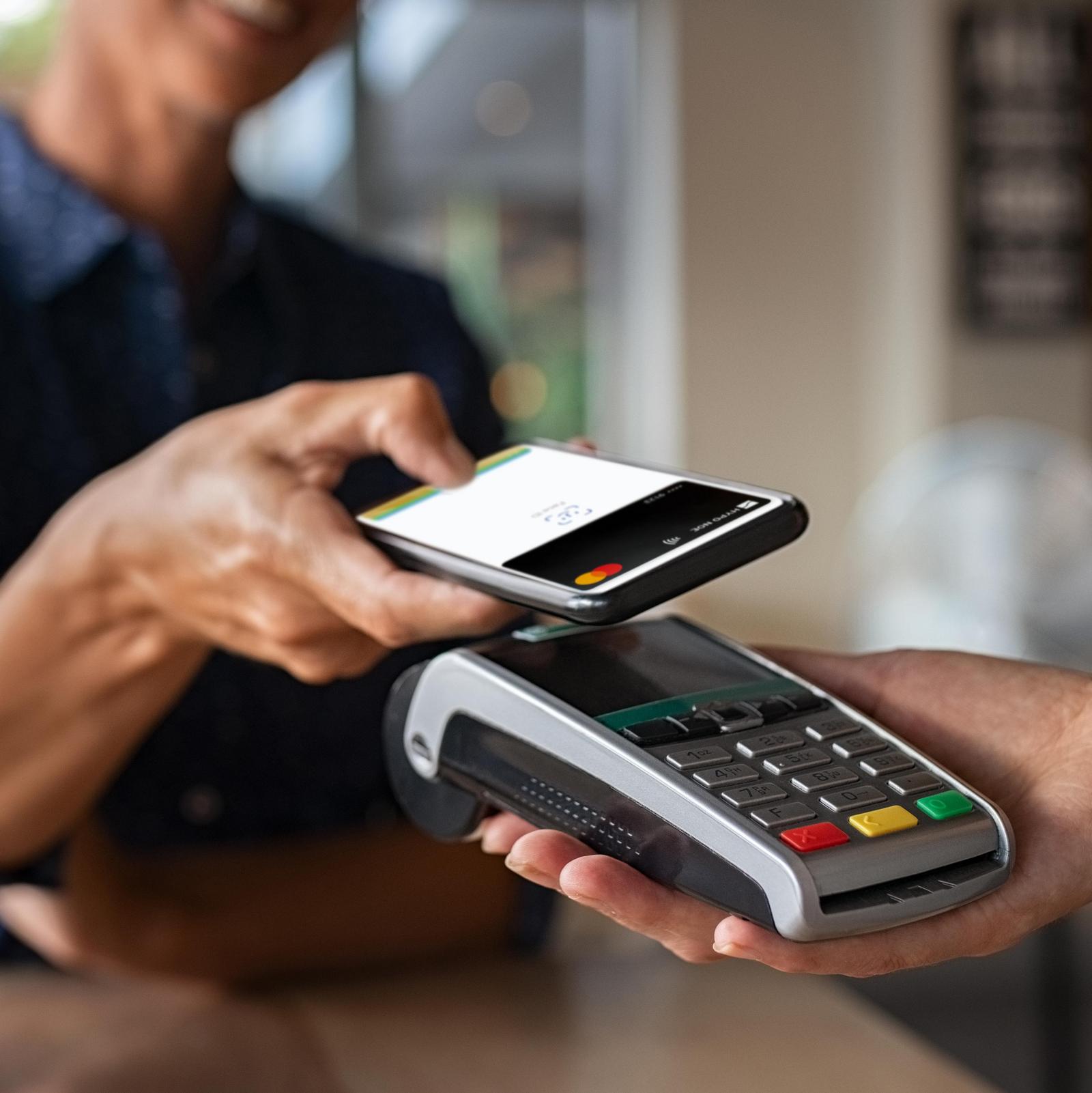 Eine Frau bezahlt im Geschäft mit ihrem iPhone und Apple Pay